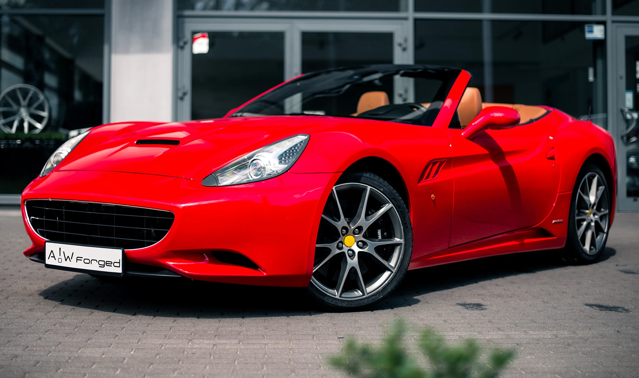 Czerwony kabriolet Ferrari California z brązowym wnętrzem na zewnątrz.